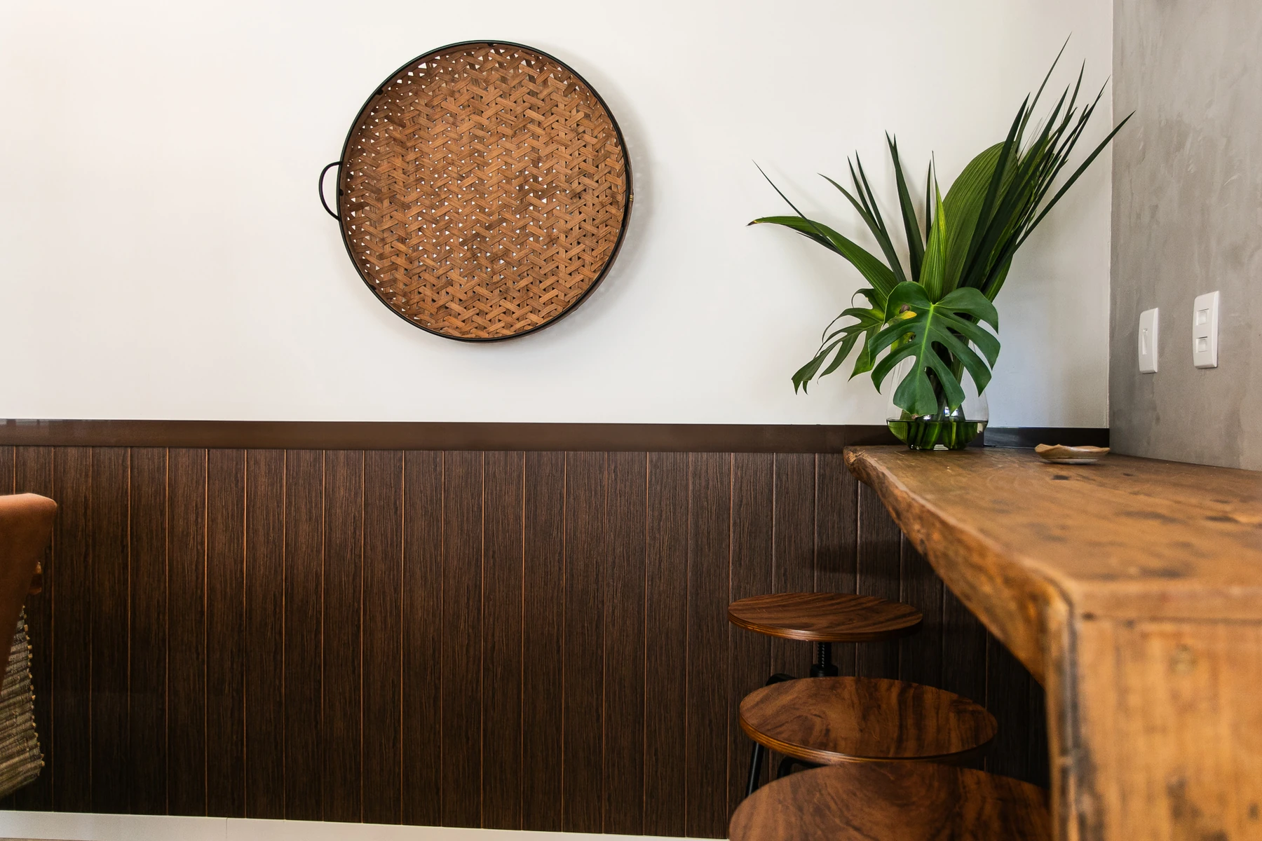 Barra de madera con banquetas, una planta y revestimiento Revyl a media altura