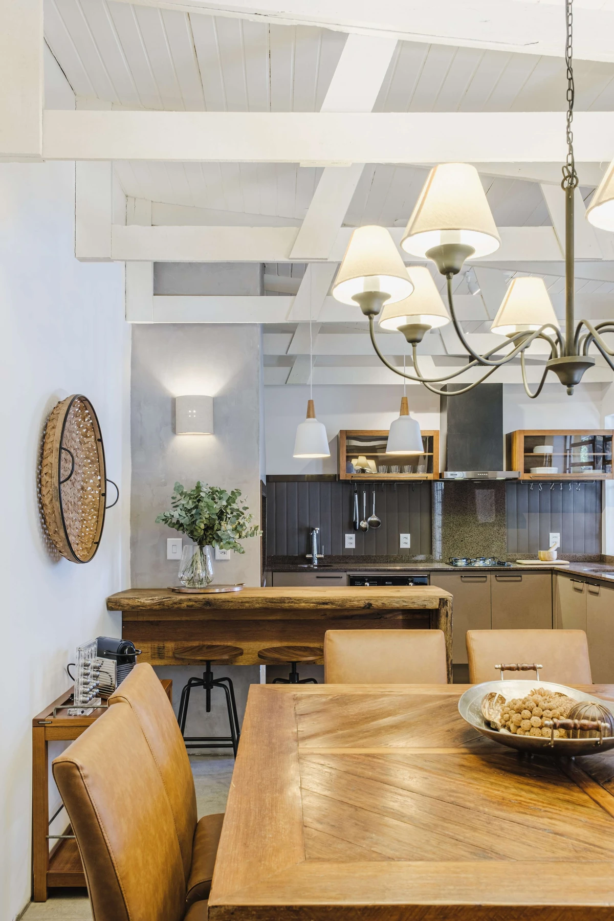 Comedor con mesa de madera y vigas blancas, integrado a un ambiente con Revyl